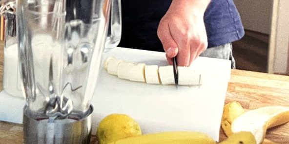 Eine Banane wird mit einer Hand geschnitten.